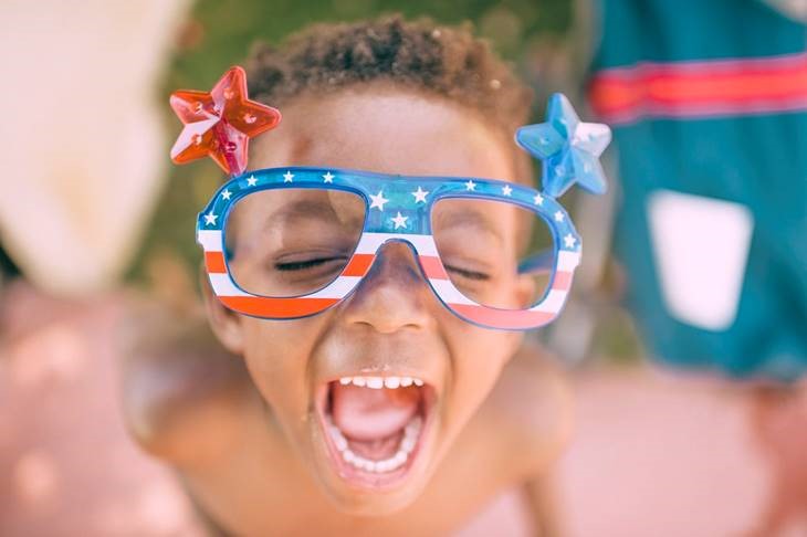 Child wearing fun, oversized stars and stripes glasses laughing
