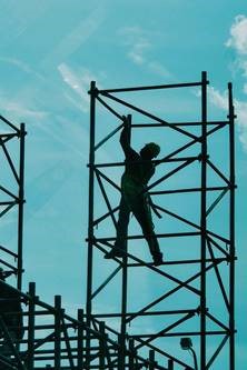 Man in a hard hat climbing some scaffolding