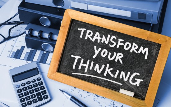 Folders, calculator and pen with a chalkboard sign saying 'transform your thinking'