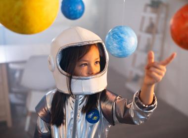 Young girl in a space suit looking at planets