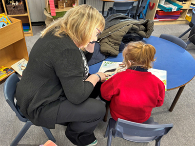 Photo of teacher helping young person to read
