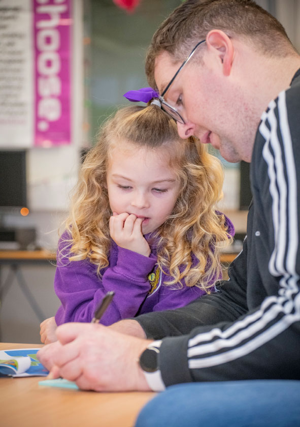 Adult male writing on a post it note with a young girl watching him